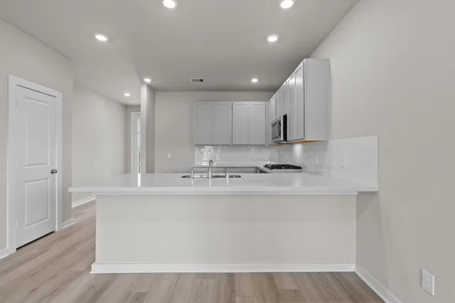 a large kitchen with stainless steel appliances granite countertop a sink a stove a refrigerator and cabinets