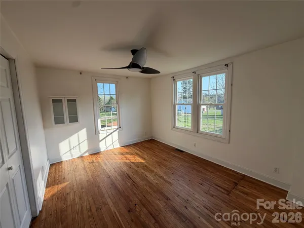 a view of an empty room with a window and wooden floor
