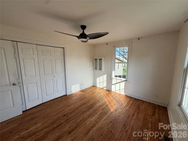 a view of empty room with wooden floor and fan