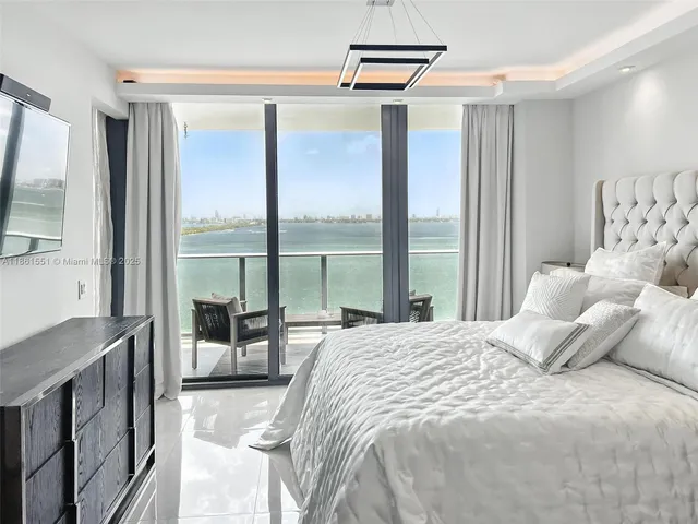 a bedroom with a large bed and a flat tv screen