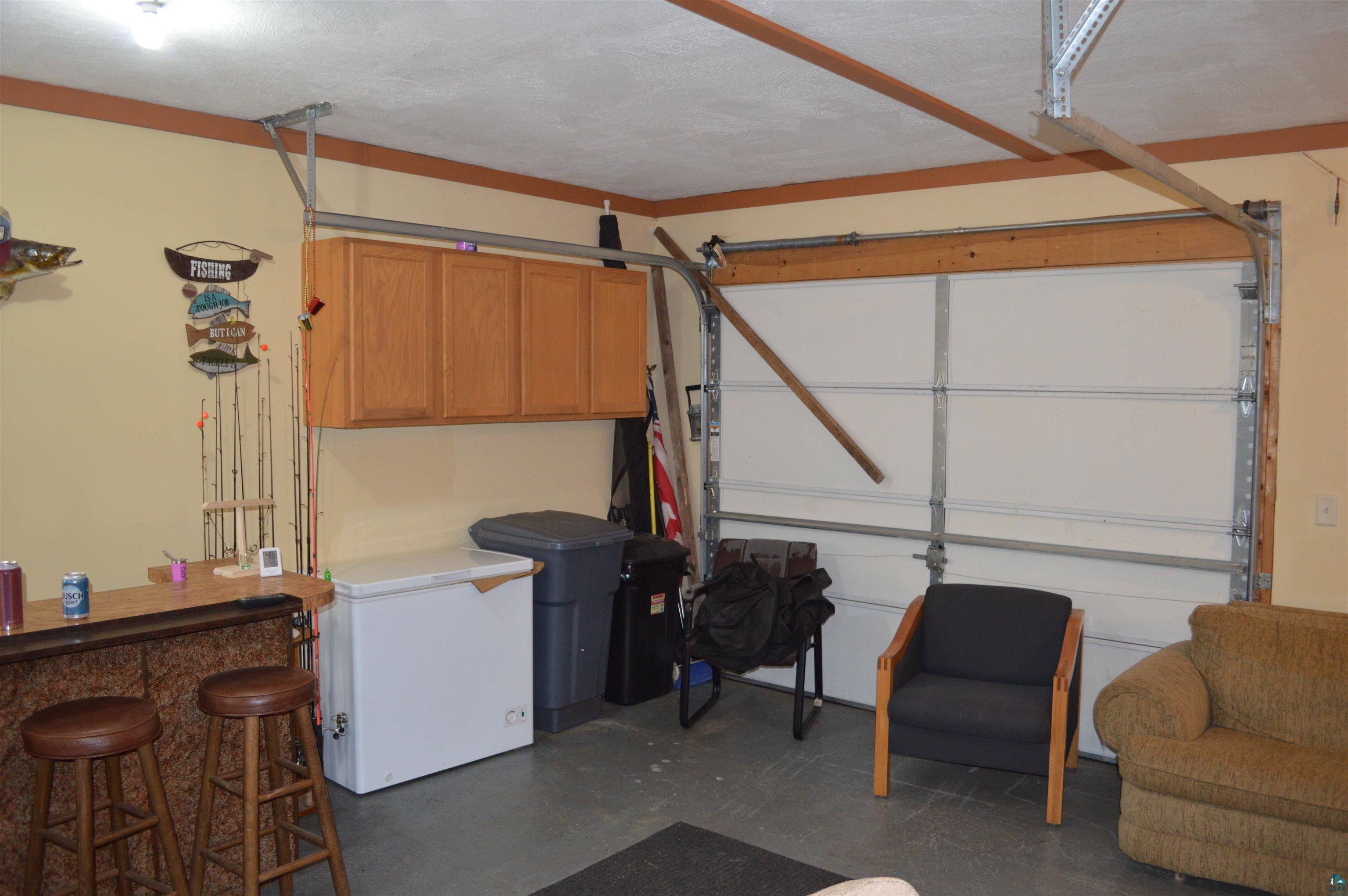 8467 County Rd P Lake Nebagamon, WI 54849 - Photo 13 of 25 Garage interior featuring a concrete floor, light yellow walls, and a white overhead door