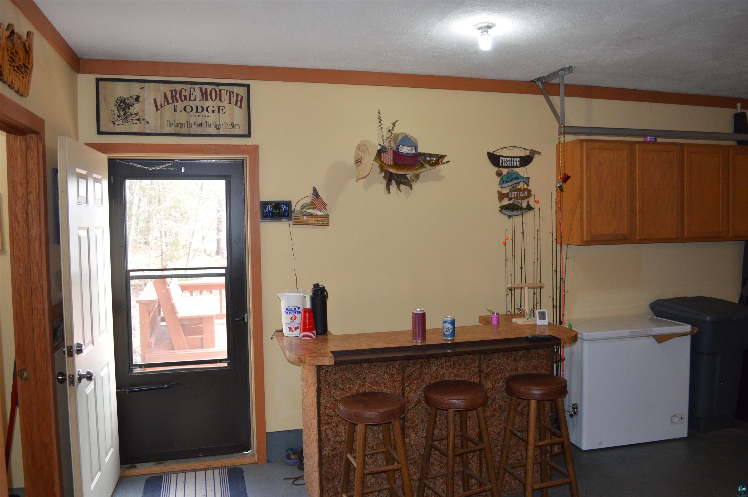 8467 County Rd P Lake Nebagamon, WI 54849 - Photo 5 of 25 Recreational space with a built-in bar featuring a textured wood-finish facade and seating for three