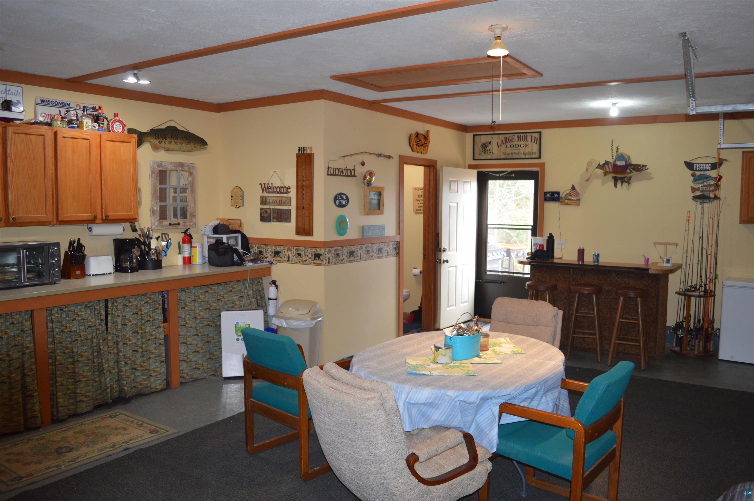 8467 County Rd P Lake Nebagamon, WI 54849 - Photo 6 of 25 Spacious room featuring a casual dining area, a built-in bar with barstools, and a functional kitchen counter with upper cabinetry