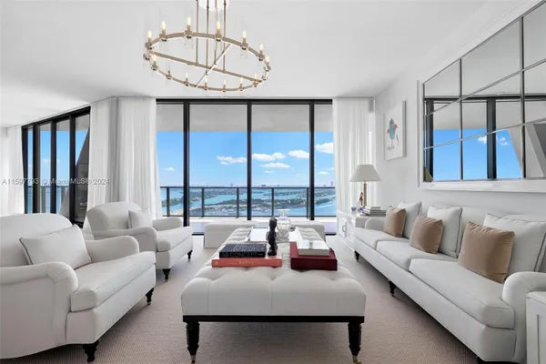 a living room with furniture large windows and a chandelier