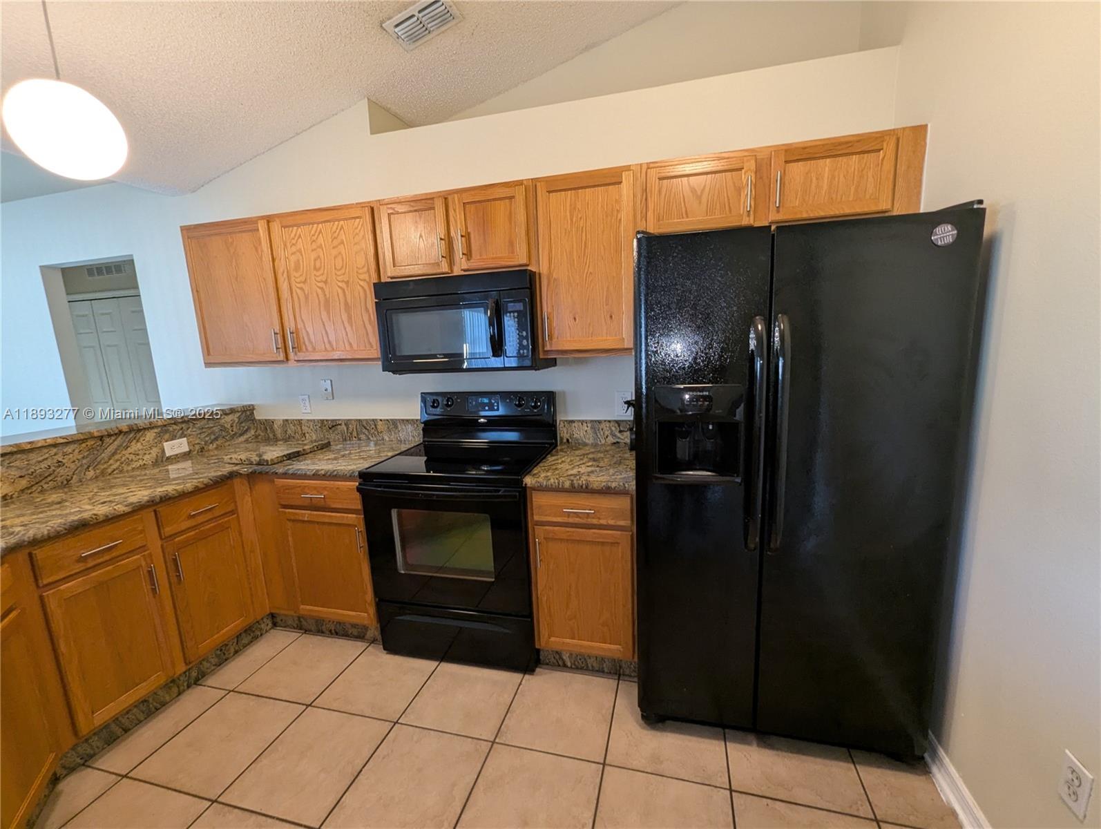 78 Pine Grove Drive Palm Coast, FL 32164 - Photo 22 of 49 a kitchen with granite countertop a refrigerator and a stove top oven