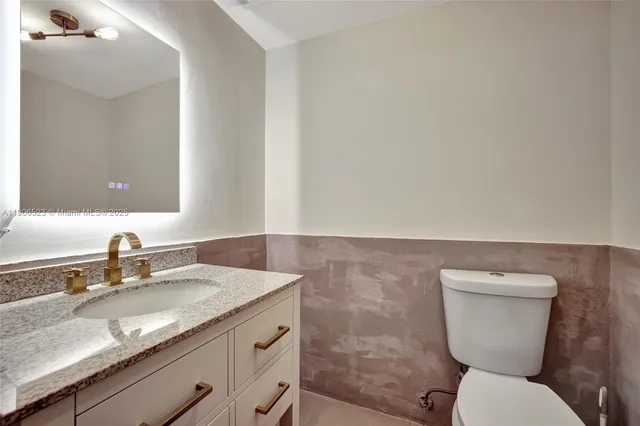 a bathroom with a granite countertop toilet sink and mirror