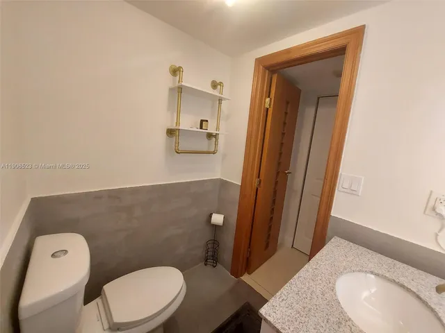 a bathroom with a granite countertop toilet and a sink