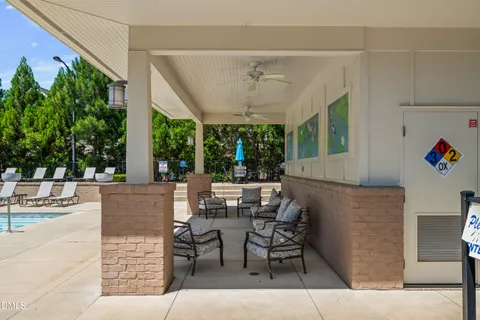a view of a patio with table and chairs potted plants and floor to ceiling window