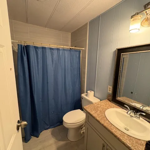 a bathroom with a granite countertop toilet sink and mirror