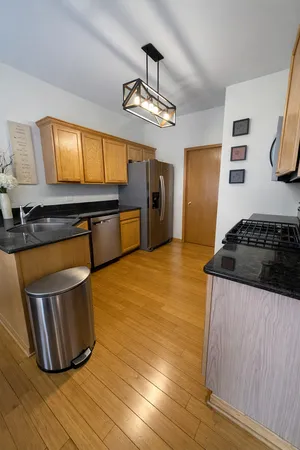 a kitchen with stainless steel appliances granite countertop a sink a stove and a wooden floors