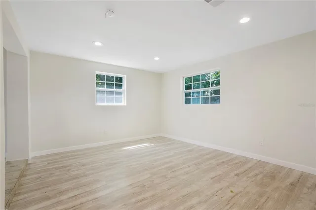 an empty room with wooden floor and window