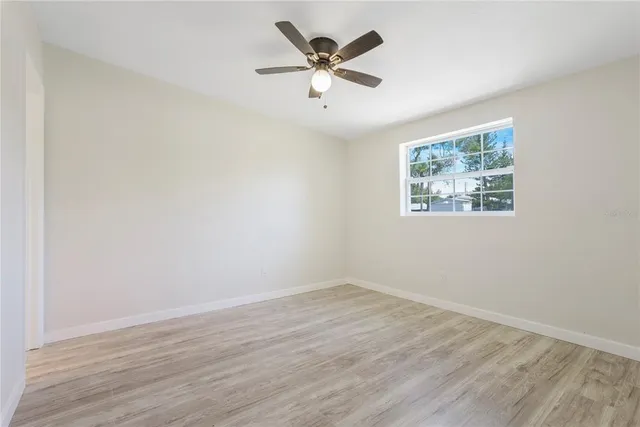 an empty room with wooden floor and ceiling fan