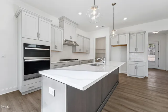 a large kitchen with stainless steel appliances kitchen island a large counter top and white cabinets