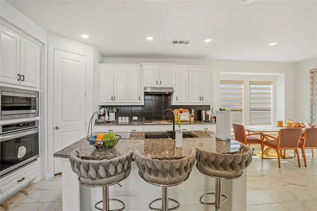 a kitchen with stainless steel appliances kitchen island granite countertop a table and chairs