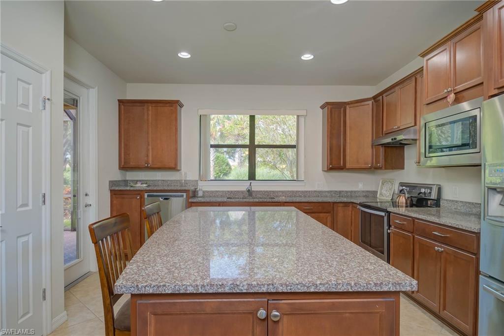 5211 Ciatto Way Ave Maria, FL 34142 - Photo 8 of 31 a kitchen with granite countertop kitchen island stainless steel appliances a sink stove and cabinets