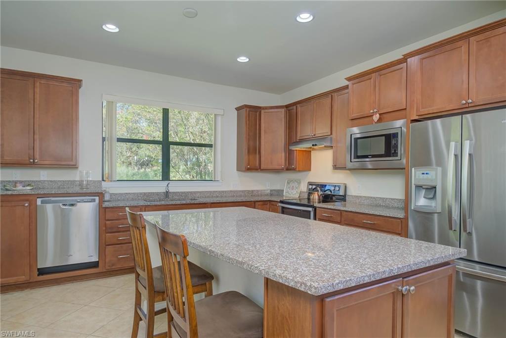 5211 Ciatto Way Ave Maria, FL 34142 - Photo 10 of 31 a kitchen with stainless steel appliances granite countertop a kitchen island hardwood floor sink and stove