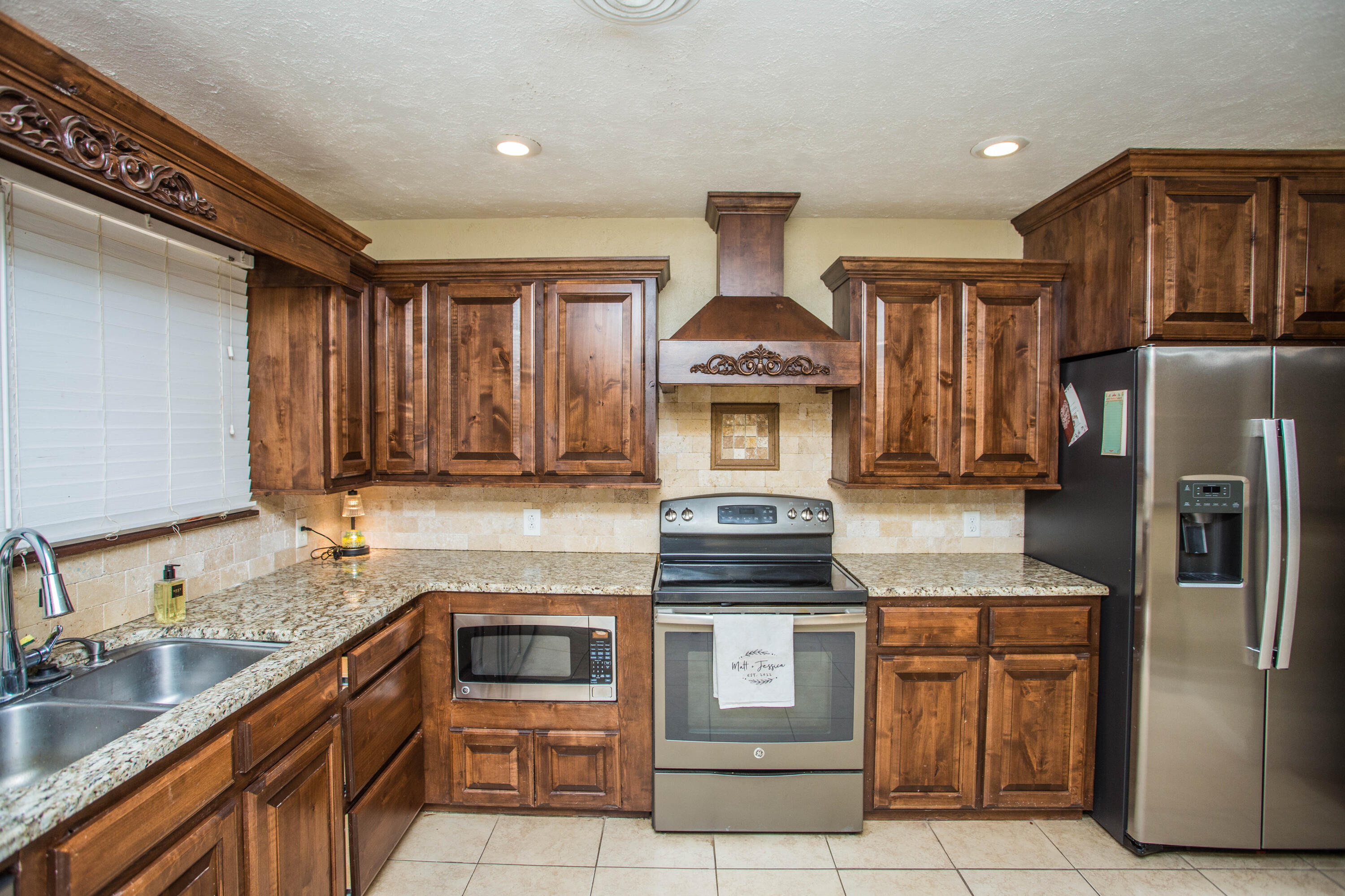 1550 West Lynn Street Slaton, TX 79364 - Photo 12 of 54 a kitchen with stainless steel appliances granite countertop a stove a sink and a refrigerator
