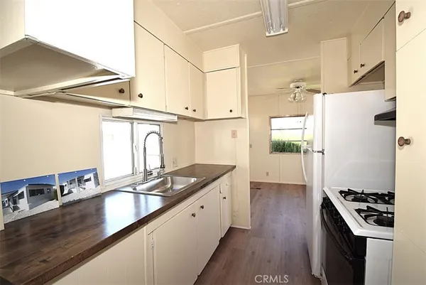 a kitchen with granite countertop a refrigerator a sink and wooden floor