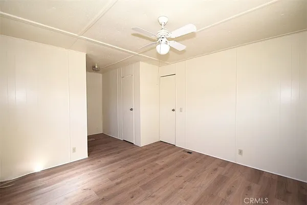 an empty room with wooden floor and fan