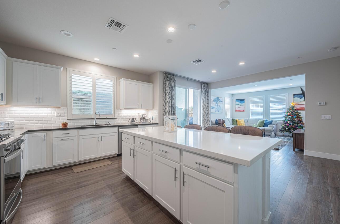 19130 Fallingwater Lane Marina, CA 93933 - Photo 11 of 43 a large white kitchen with kitchen island a sink dishwasher a stove and white cabinets with wooden floor