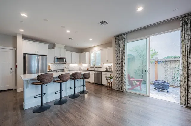a kitchen with stainless steel appliances kitchen island granite countertop a table chairs in it and wooden floors