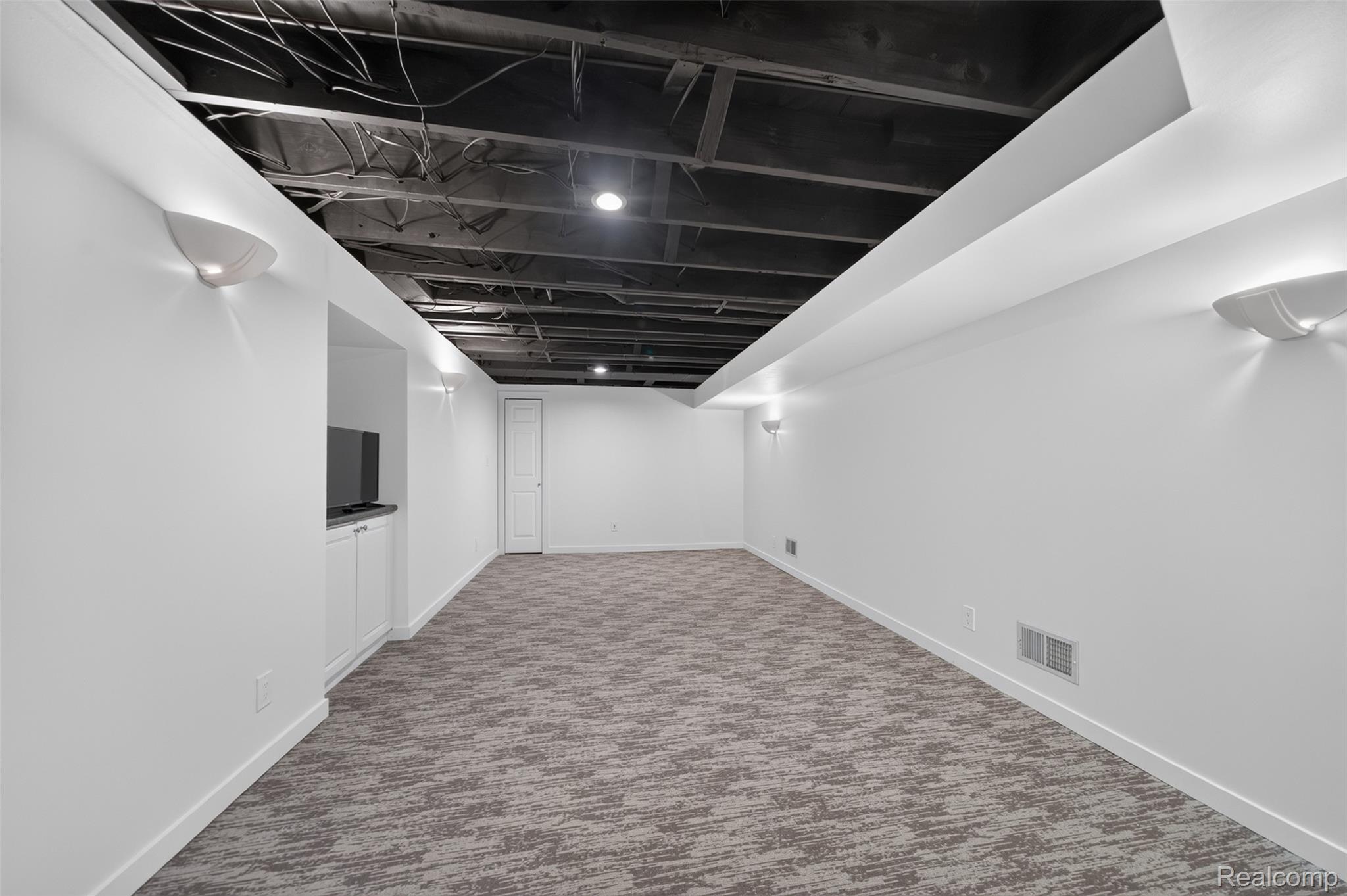 1236 Chaffer Drive Rochester, MI 48306 - Photo 51 of 76 Spacious room featuring a patterned carpet, white walls, built-in cabinetry with a dark countertop, white baseboards, and wall-mounted sconces