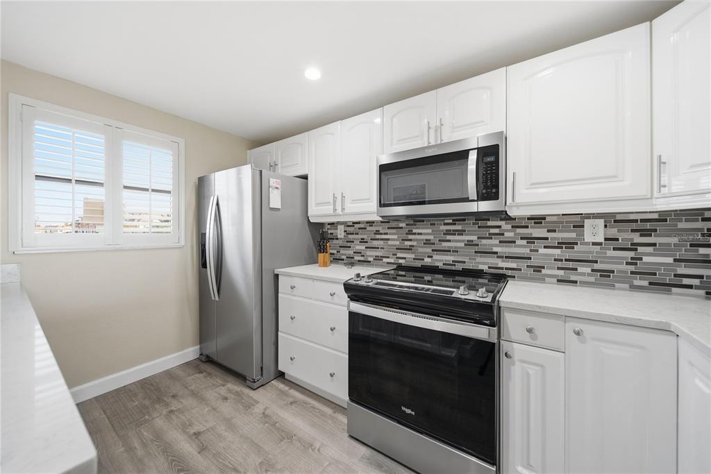 17580 Gulf Boulevard, Unit 302 Redington Shores, FL 33708 - Photo 13 of 37 a kitchen with stainless steel appliances white cabinets a stove top oven a sink and dishwasher