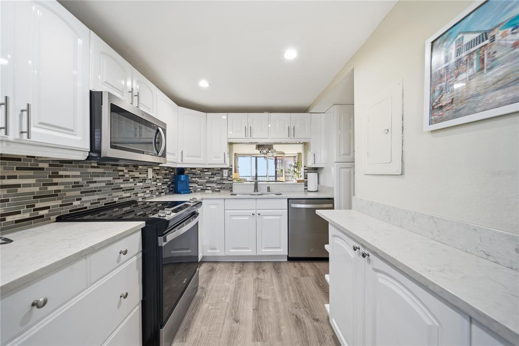 17580 Gulf Boulevard, Unit 302 Redington Shores, FL 33708 - Photo 14 of 37 a kitchen with granite countertop white cabinets stainless steel appliances a sink and a counter space