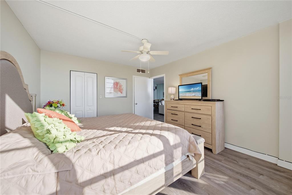 17580 Gulf Boulevard, Unit 302 Redington Shores, FL 33708 - Photo 17 of 37 a bedroom with a bed a dresser and a chandelier