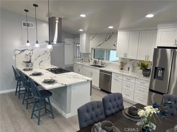 a kitchen with stainless steel appliances kitchen island granite countertop a sink refrigerator and cabinets