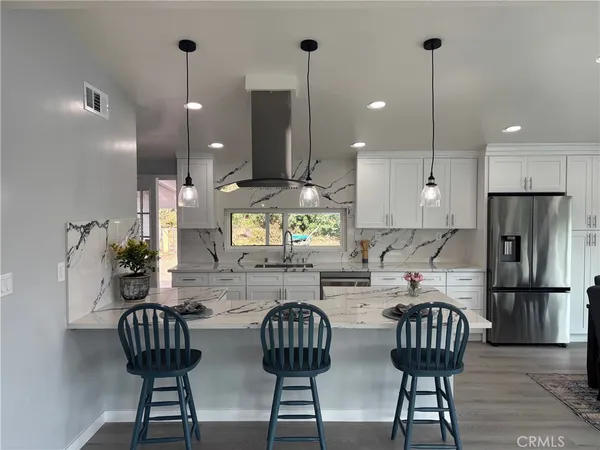 a kitchen with stainless steel appliances granite countertop a dining table chairs and a refrigerator