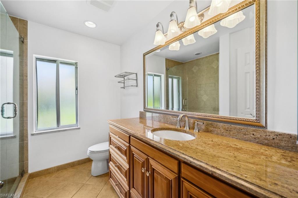 1986 Imperial Golf Course Boulevard Naples, FL 34110 - Photo 24 of 38 a bathroom with a granite countertop sink a toilet and mirror