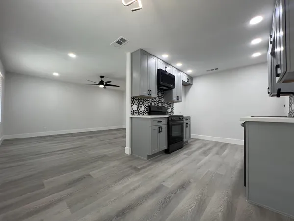 a kitchen with stainless steel appliances a stove top oven a sink a counter space and cabinets