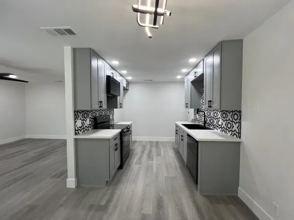 a kitchen with kitchen island granite countertop a sink cabinets and wooden floor