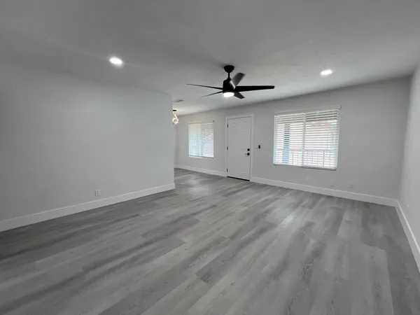a view of an empty room with a window and a kitchen