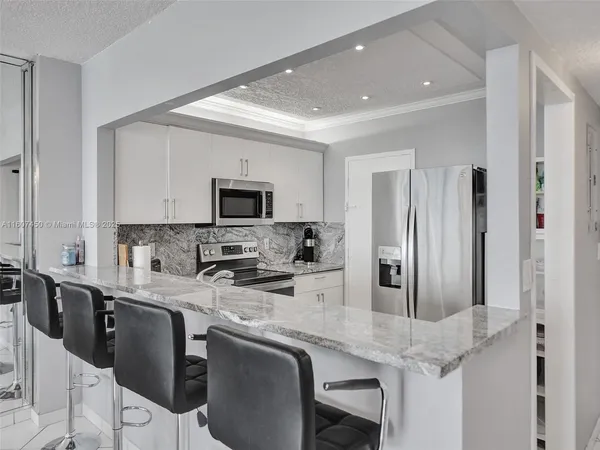 a kitchen with stainless steel appliances granite countertop a stove a sink a microwave a refrigerator and cabinets