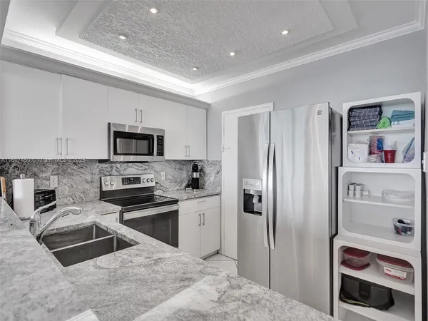 a kitchen with stainless steel appliances granite countertop a refrigerator a stove and a sink with wooden floor