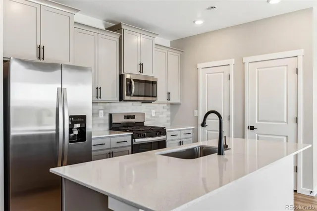 a kitchen with stainless steel appliances a refrigerator a sink a stove and cabinets