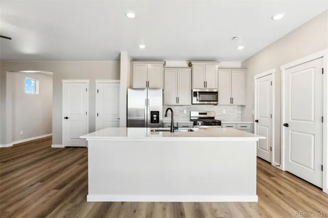 a view of a kitchen with stainless steel appliances a refrigerator and a stove top oven