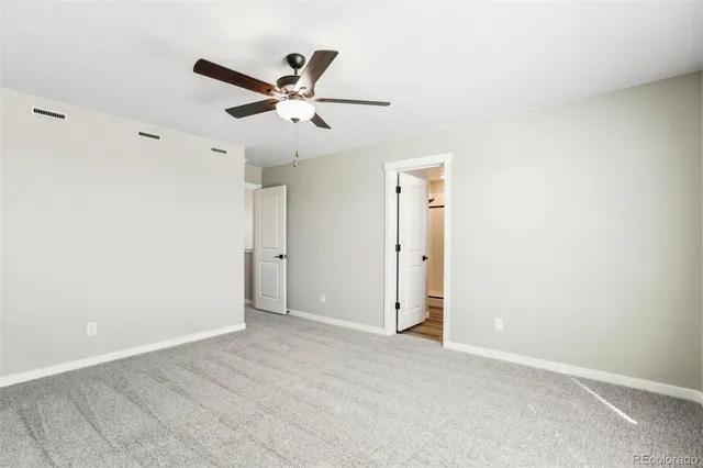 an empty room with a ceiling fan and window