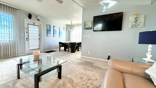 a view of a white house with a big yard and potted plants and large trees