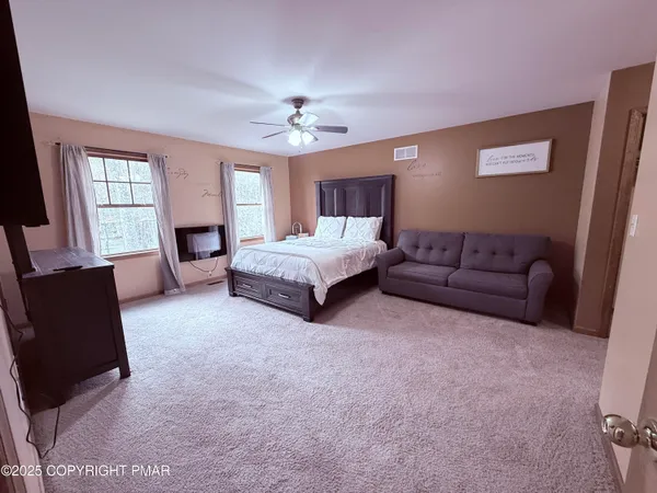 a spacious bedroom with a bed couch and window