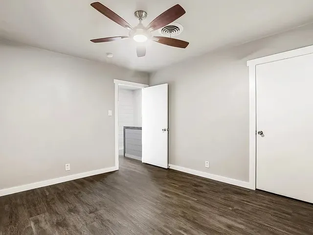 an empty room with wooden floor and ceiling fan