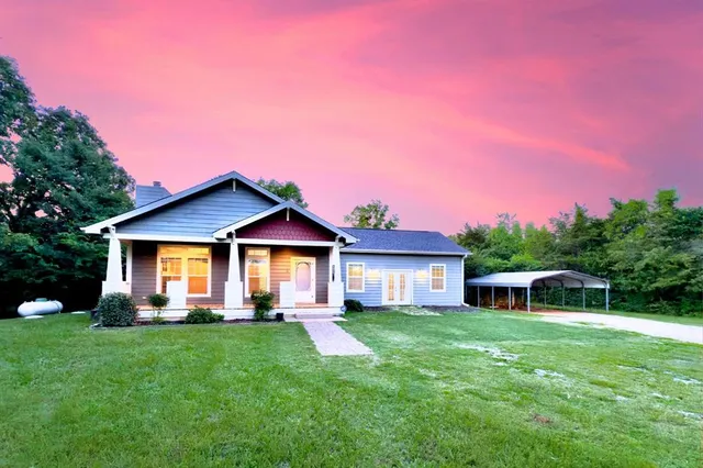 a front view of a house with a yard and green space