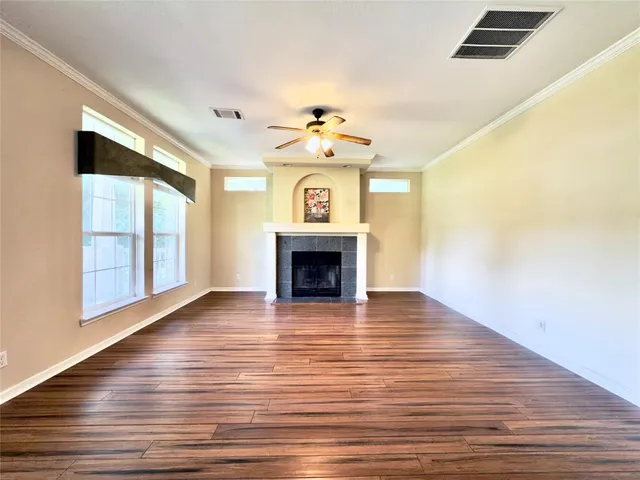 a view of an empty room with wooden floor fireplace and a window