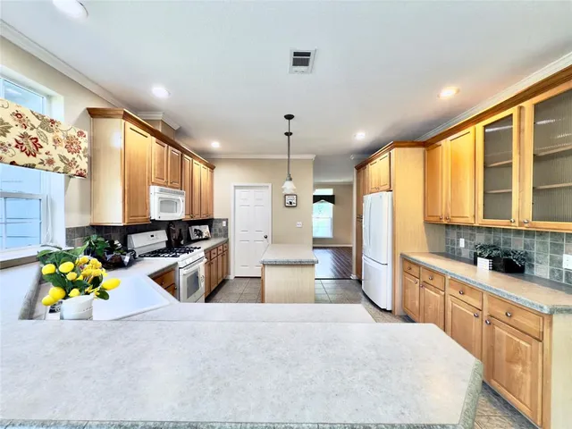 a large white kitchen with stainless steel appliances kitchen island granite countertop a sink and cabinets