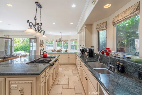a kitchen with kitchen island granite countertop a stove a sink a center island and windows