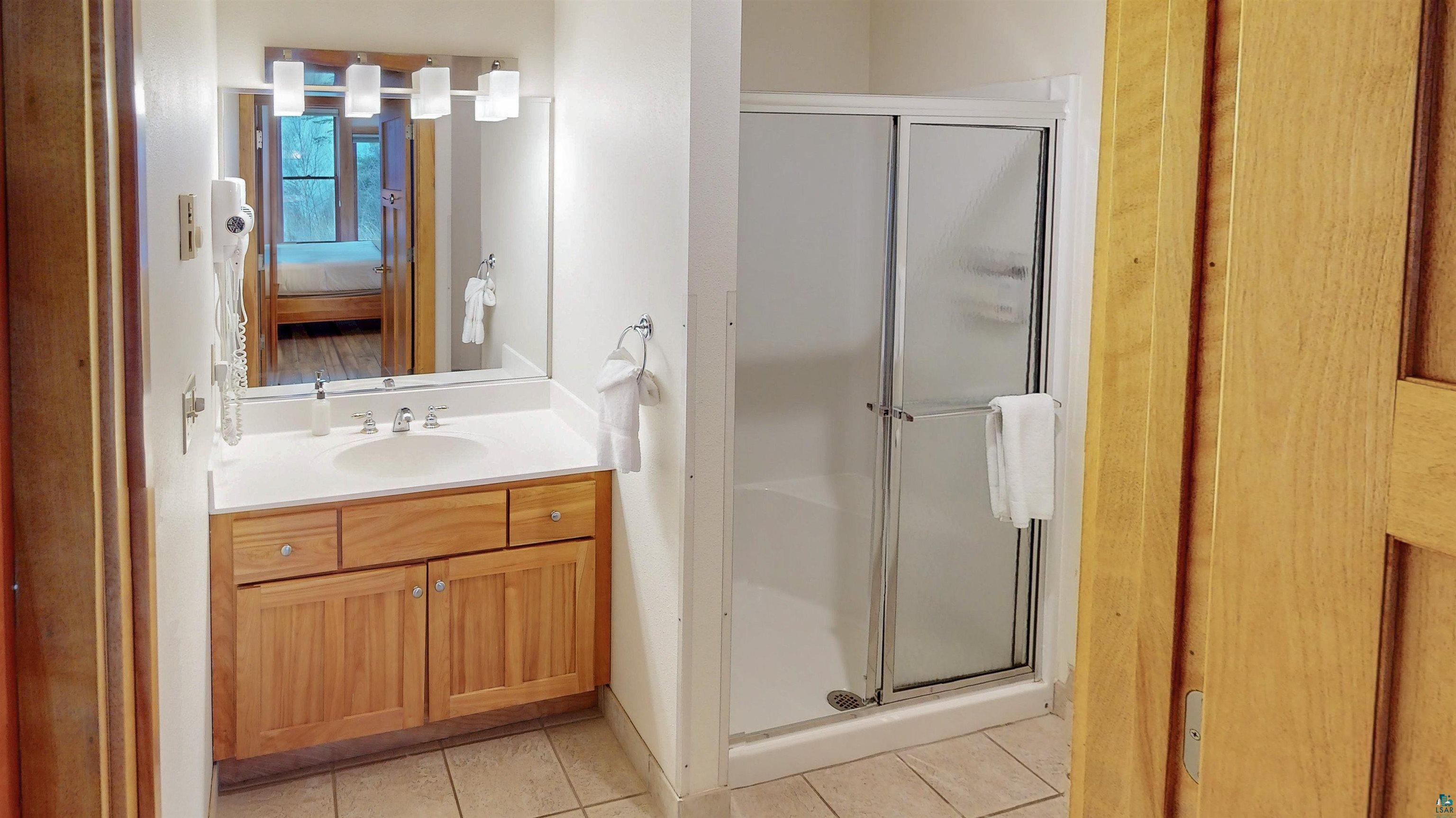 504-506 Poplar River Road, Unit 505 Lutsen, MN 55612 - Photo 15 of 39 Bathroom featuring a wood-finish vanity with a single sink, an integrated countertop, and a mirrored wall