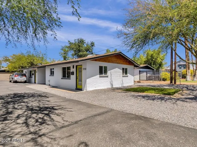 a view of a house with a yard and large trees