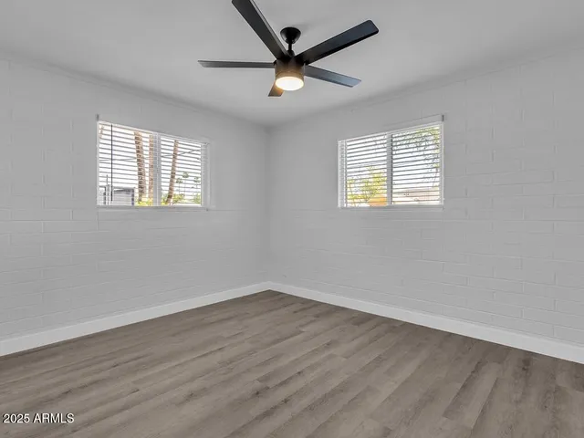 a view of empty room with wooden floor and fan